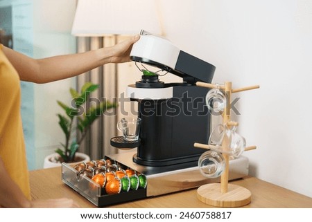 hand making Espresso Coffee by Coffee Maker Machine with Capsule of roasted coffee bean on wood table bar. Daily beverage drink at Home, Apartment and Office concept