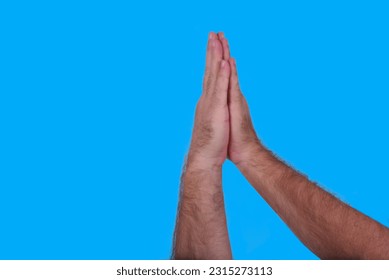 hand making peace and love gesture raising hand cupped together isolated on blue background - Shutterstock ID 2315273113