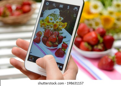 Hand making photo of strawberries on mobile phone for social network - Powered by Shutterstock