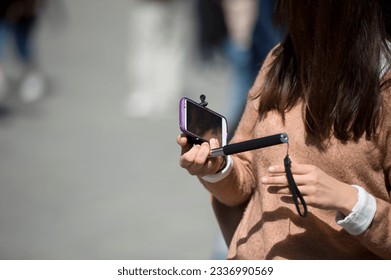 Hand making a selfie using remote control and extension tripod