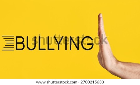 Hand making a stop gesture, preventing the word bullying from advancing. Concept of anti-bullying, protection and awareness