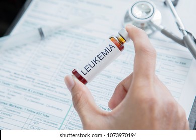 Hand Of Male Doctor Holding A Small Bottle Of Drug For Leukemia Disease With Medical Record Form Background In The Hospital