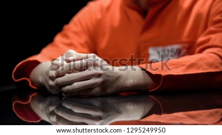 Hand of male prisoner, inmate giving evidence in detention room, cooperation