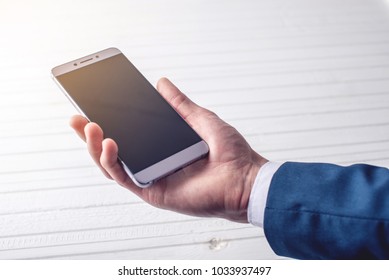 Hand Man Businessman In A Suit Holding A Phone. The Concept Of Apps For Business