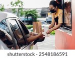 Hand Man in car receiving coffee in drive thru fast food restaurant. Staff serving takeaway order for driver in delivery window. Drive through and takeaway for buy fast food for protect covid19.