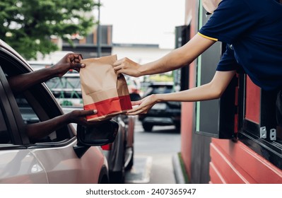 Hand Man in car receiving coffee in drive thru fast food restaurant. Staff serving takeaway order for driver in delivery window. Drive through and takeaway for buy fast food for protect covid19.