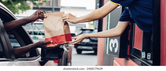 Hand Man in car receiving coffee in drive thru fast food restaurant. Staff serving takeaway order for driver in delivery window. Drive through and takeaway for buy fast food for protect covid19.