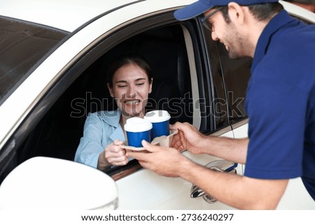 Hand Man in car receiving coffee in drive thru fast food restaurant. Staff serving takeaway order for driver in delivery window. Drive through and takeaway for buy fast food for protect covid19.