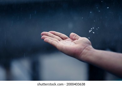 Hand of man catching raindrops. - Shutterstock ID 2000403638