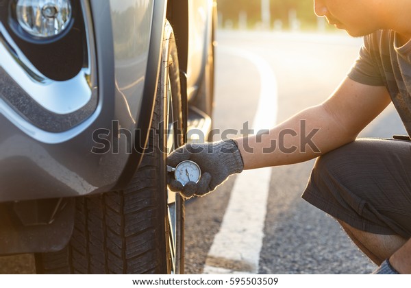 Hand of man checking air pressure and filling air in\
the tires of his car.