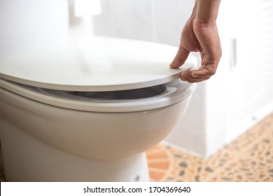 hand of a man is closing the toilet lid. Prevents the spread of germs and viruses, Prevent air pollution, Concept of prevention of infection.