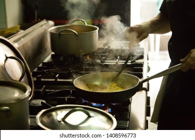 Hand Man Cooking With A Steel Pot On The Stove In The Kitchen