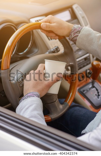 hand\
man driving an expensive car with a cup of\
coffee