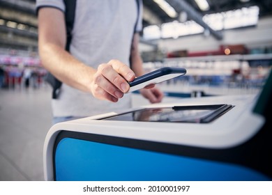 Hand Of Man During  Using Self Service Check-in Machine. Passenger Scanning Ticket On Smart Phone At Airport Terminal.
