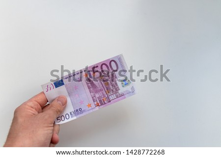 Hand of a man holding a 500 euro bank note as reward, credit or side job with a blurred white background