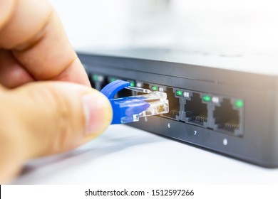 Hand of man holding The blue network cables connect port switch on white table concept internet network connection - Powered by Shutterstock