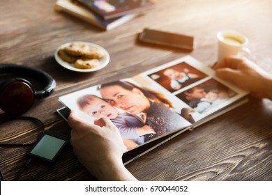 the Hand man holding a family photo album  against the background of the a wooden table
