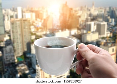 Hand of a man holding a hot coffee cup with smoke at the new morning on a modern city background - Powered by Shutterstock