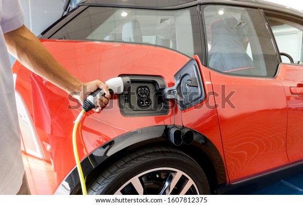 Hand of man holding plug for\
charge electric power into Battery of Electric car on charge\
station electric mobility environment friendly with copy\
space.	
