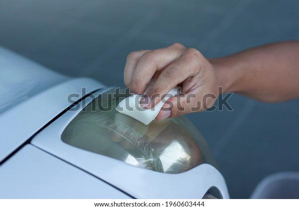 Hand of man holding a sponge to\
Polishing the car headlights that are yellow to clear\
up.
