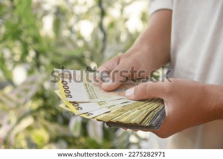 Hand of man holding Sri Lanka rupees banknotes of different denominations. Close up. Outdoors.
