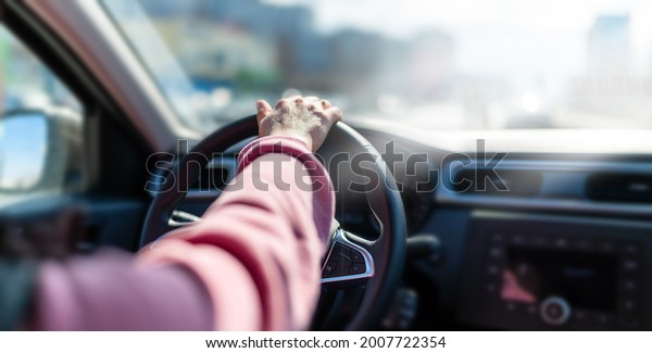 The hand of a man holding a steering wheel\
in the car. A man woman driving a\
car