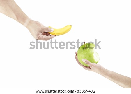 A hand of a man holding a yellow banana offering to a woman hand holding a green apple that is half eaten, isolated against white.