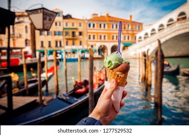 Hand Man Holds An Italian Ice Cream On Background Of Grand Canal And Handol In Venice, Italy. Concept Tourism.