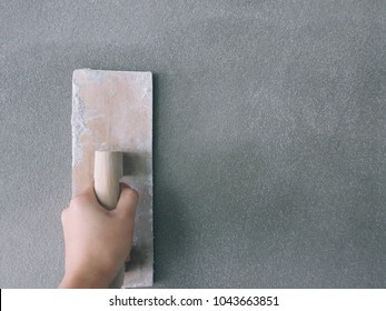 Hand of a man holds a trowel for plastering a cement wall or skimming coating on plaster walls