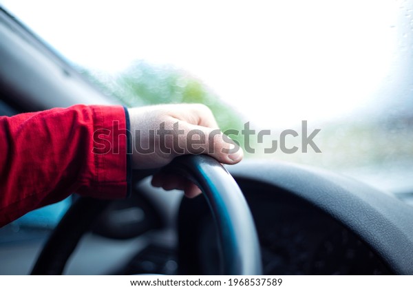 Hand of a\
man on the steering wheel of a car\
closeup