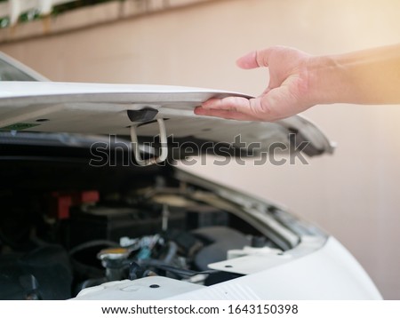 hand of a man opening the bonnet To check general car conditions, Engine, oil, radiator.