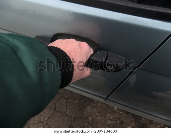 The hand of a man\
opening the car door
