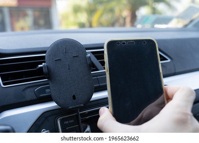 Hand of man placing cellphone on mobile holder in car interior. Vehicle modern equipment device