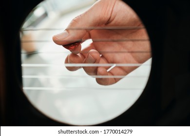 Hand Of Man Playing Acoustic Guitar Viewed From Inside Hole