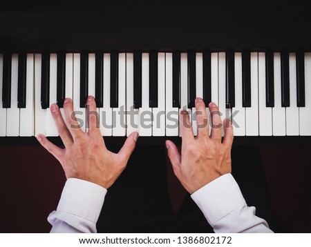 Hand man playing piano. Classical music instrument. Top view. Vintage color tone with dark vignette.