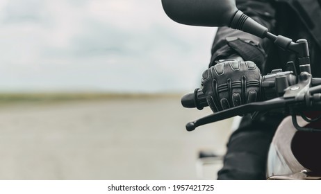 Hand of a man in protective motorcycle gloves holds a black motorcycle, close up - Powered by Shutterstock