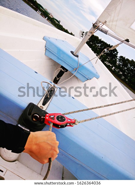 Hand of man pulls the rope controlling the sail on\
sailing boat.