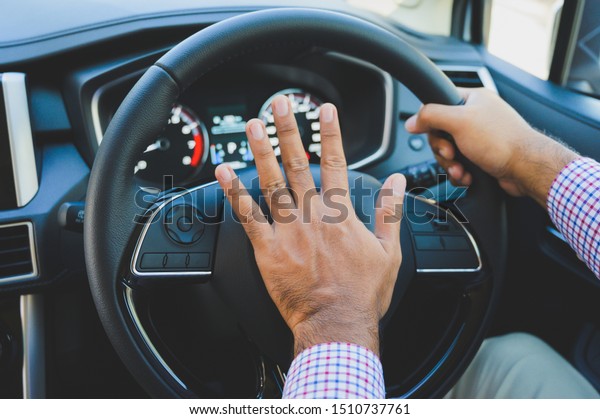 Hand man pushing\
car horn while driving\
car.