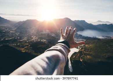 Hand Of A Man Reaching Out The Beautiful Landscape. POV Shot Of Human Hand On A Sunny Day.