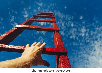 Hand Of Man Reaching For Red Ladder Leading To A Blue Sky. Development motivation Career Growth Concept
