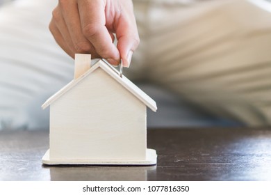 Hand Of Man Saving Money In Piggy Bank For Future Property.