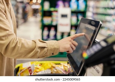 Hand of a man at self-service checkout in supermarket.