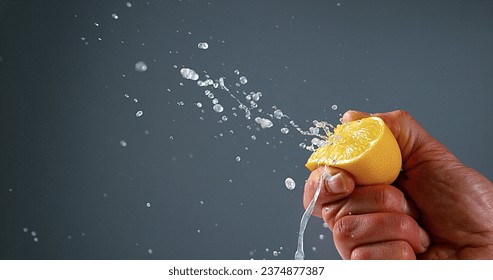 Hand of Man Squeezing Lemon, citrus limonum against Black Background