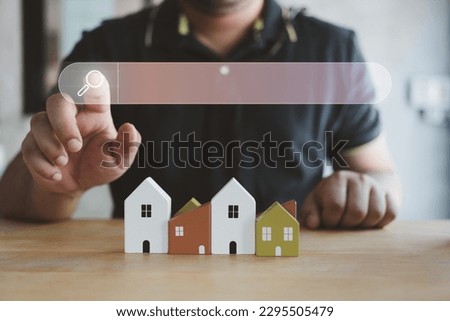 Hand of man touching magnifying glass icon search for find information data about home on top of a model wood house. Search advertising for rent or buy a home. Search Engine Optimization