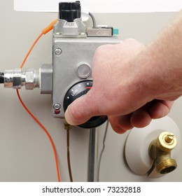 Hand Of A Man Turning Down Household Gas Water Heater Temperature.