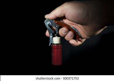 hand man using corkscrew to open a bottle of wine