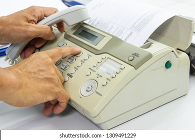 Hand man are using a fax machine send paper in the office Business concept 