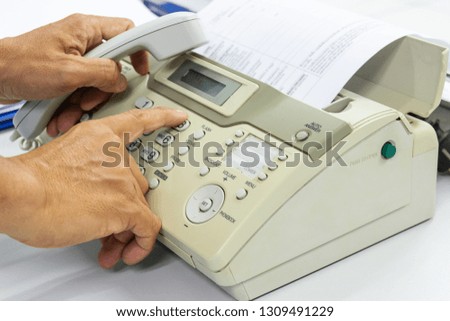 Hand man are using a fax machine send paper in the office Business concept 