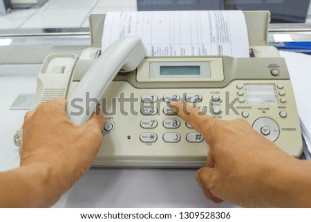 Hand man are using a fax machine send paper in the office Business concept 