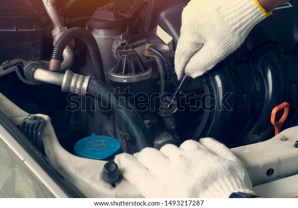 Hand of man wear white gloves maintenance \
recheck nut wrench engine cover\
area.